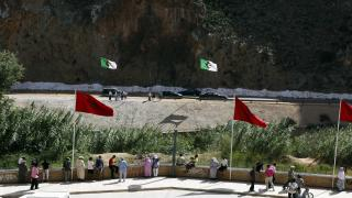 People stand near a border post on the Algerian side of the Morocco-Algeria border in the north east of Morocco July 31, 2011. Morocco's King Mohammed renewed calls on Saturday to normalise ties and reopen borders with wealthier neighbour Algeria, saying that Rabat wants to build an integrated North African economic bloc. Morocco closed the border following a 1994 Islamist militant attack in Marrakesh, which it blamed on Algeria's secret service, and the border region remains tense. REUTERS/Youssef Boudlal (MOROCCO - Tags: POLITICS)