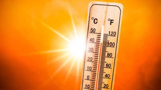 Background for a hot summer or heat wave, orange sky with with bright sun and thermometer